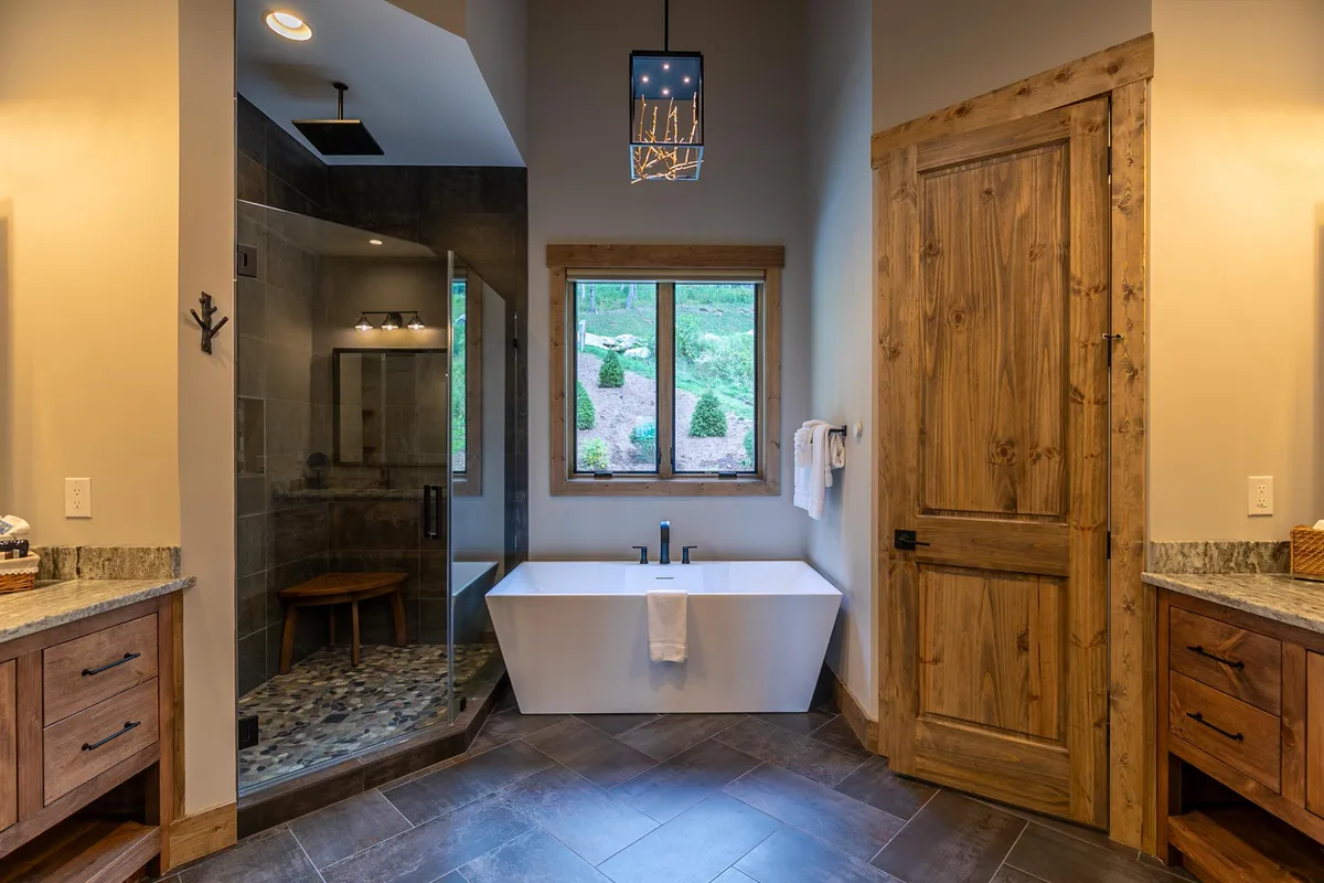 A luxurious bathroom featuring a freestanding soaking tub positioned near a window, a separate shower area, and serene natural light streaming in. The mood is tranquil, inviting long, soothing soaks and moments of solitude—emphasizing a spa-inspired bathing experience.